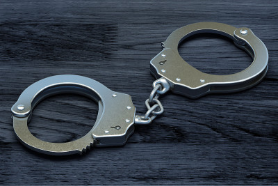 刑事司法与有罪判决概念:桌上的钢手铐。深色木制背景的警察金属手铐