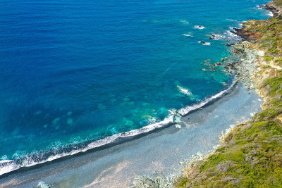 Plage de Nonza的全景鸟瞰图，在悬崖底部的长长的黑色海滩上矗立着Nonza小镇，在Cap