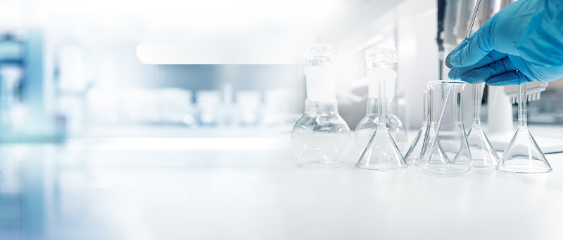 拥有医用化学实验室旗帜背景的试管和烧瓶科学家的手