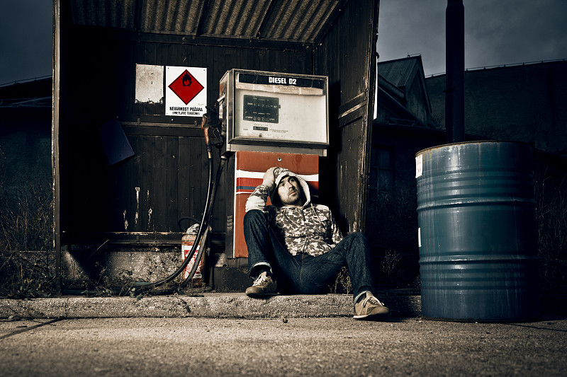 Depressed man sitting at abandoned gas station