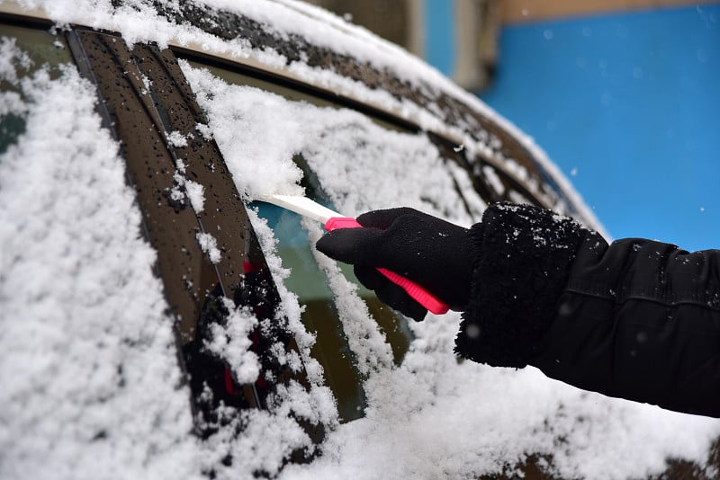 清除汽车挡风玻璃上的积雪。在冬天清洁车窗。