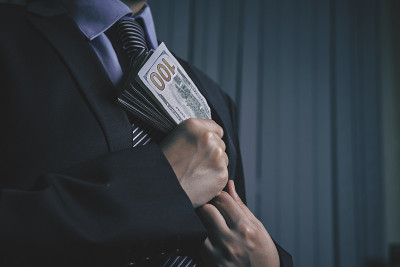 一个政府官员把一堆钱放进他的口袋里