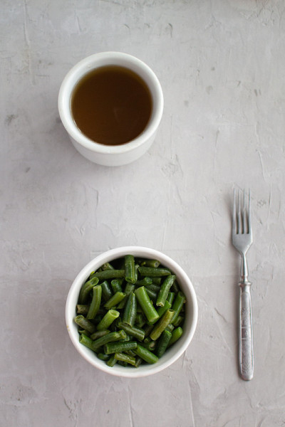 用橄榄油煮熟的四季豆，还有大蒜和柠檬。一杯绿茶。