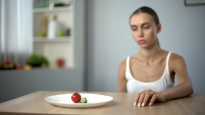 疲惫苗条的女人看着一小份早餐，自我毁灭