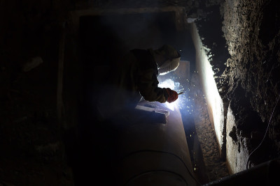 male worker welds steel pipe of household heating 
