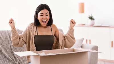 兴奋的亚洲女士打开包裹后网上购物