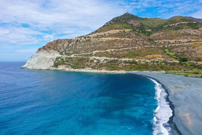 Plage de Nonza的全景鸟瞰图，在悬崖底部的长长的黑色海滩上矗立着Nonza小镇，在Cap