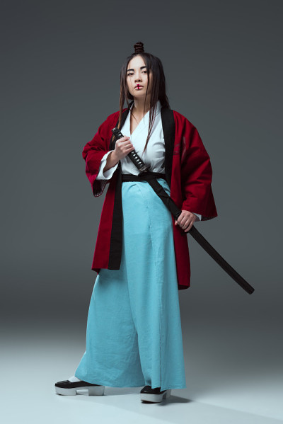 穿着和服的武士拿着武士刀，看着灰色的相机
