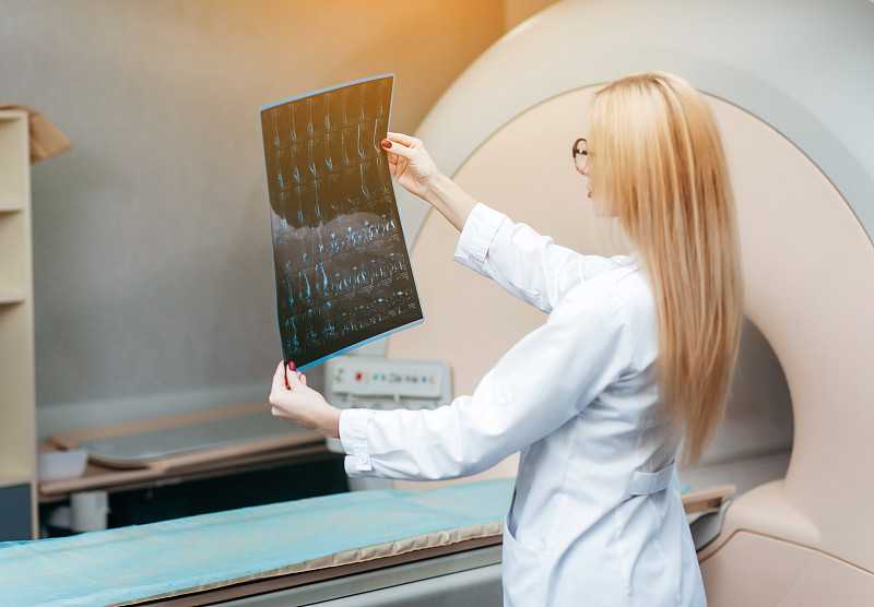 美丽的女孩医生检查核磁共振图像