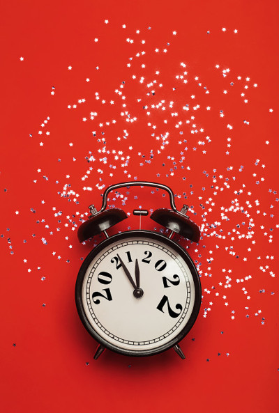 新的2022年背景概念。在新年前夜和圣诞节，红色背景的闹钟将2021年改为2022年。