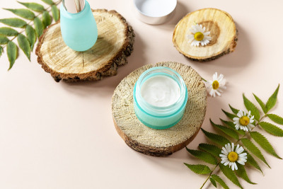 日常卫生及女性健康护肤。化妆品霜和面部血清与洋甘菊花在一个蓝色的背景。SPA天然有机美容产品。副本的