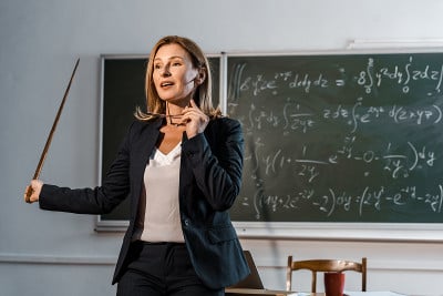 女教师手持眼镜，手持木制教鞭，在课堂上讲解数学方程