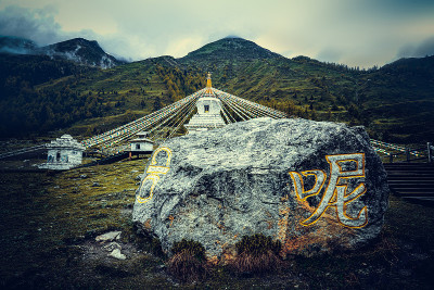 中国四川省四姑娘山双桥沟的宝塔和祈祷者。西藏白塔、经幡、玛尼石