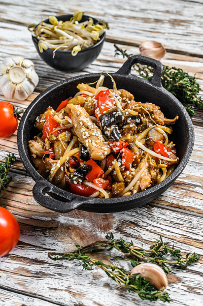 乌冬面与鸡肉和蔬菜在平底锅中煸炒。白色背景。俯视图