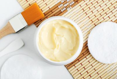 黄色面膜(香蕉面霜，乳木果头发面膜，身体黄油)在小的白色罐子里。自然的皮肤和头发概念。