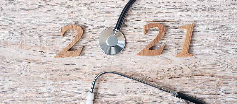 2021年，祝医疗保健、健康和医疗理念新年快乐。听诊器和木制号码在桌子的背景