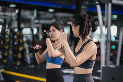 年轻的亚洲女子运动训练拳击手带手腕与教练，拳击练习运动搏击或与伙伴在健身馆锻炼健康的生活方式和自我防