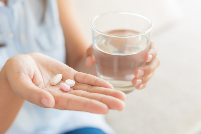 近景女子手里拿着药片、药片和一杯治头痛的水。医疗保健、医疗补充概念。