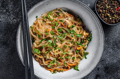 锅热的亚洲玻璃纸面条与鸡肉。黑色背景。俯视图