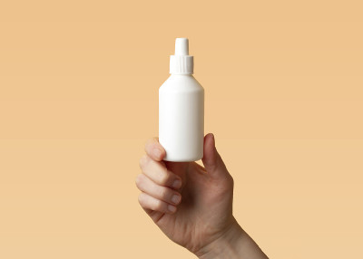 预防病毒性疾病的概念。女性的手拿着一个塑料瓶，上面有一个橙色的背景，上面是一个非碘化的消毒氯己定(氯