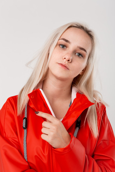 穿着红雨衣的金发女孩孤立地站在白色的背景上。准备好迎接坏天气吧。