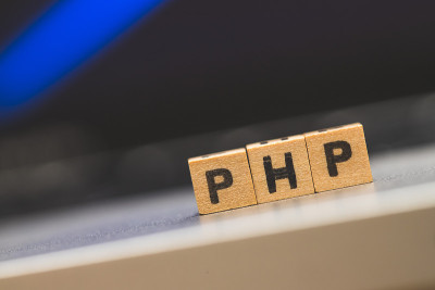 PHP编程网络语言:字母“PHP”的木制立方体躺在笔记本电脑上，概念