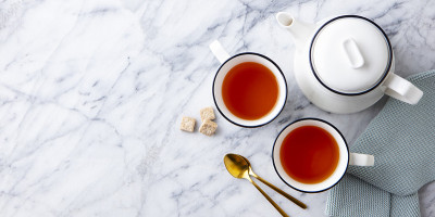 大理石背景上的茶壶茶杯里的茶。副本的空间。前视图。