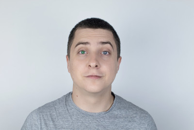 一个有着不同颜色眼睛的男人看着画框。右眼是蓝色，左眼是绿色。异色症。基因突变。多色的眼睛。