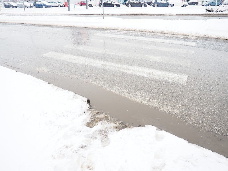 行人十字路口的雪、冰、雪泥和冬天的泥。气温在零度左右。困难的驾驶环境。汽车制动距离。交通法规。基础设