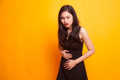 一位年轻的亚洲妇女胃痛。