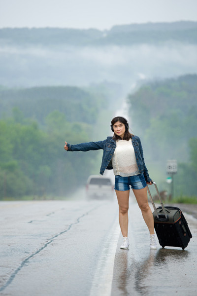 一个女人拿着箱子站在路上等我。
