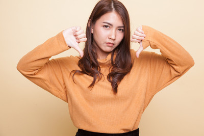 不快乐的亚洲女孩双手大拇指向下。