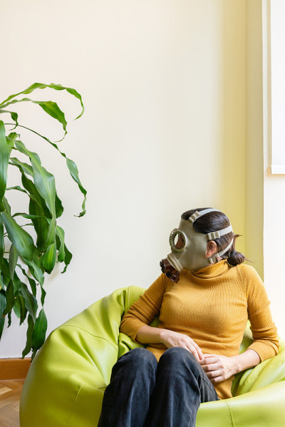 在家中健康植物附近带防毒面具的妇女的垂直视图。