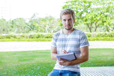 严肃的男学生拿着抄写本的肖像