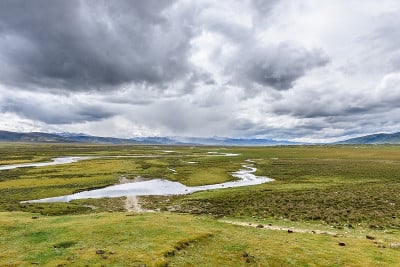 一个广阔的盆地草地景观在理塘，四川，中国。