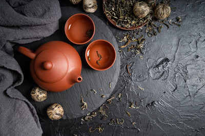 亚洲茶壶和绿茶在板岩上俯视平铺