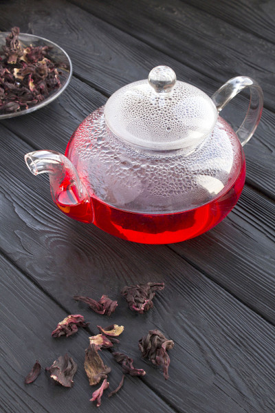 木槿或卡卡德茶在玻璃茶壶上的黑色木制背景