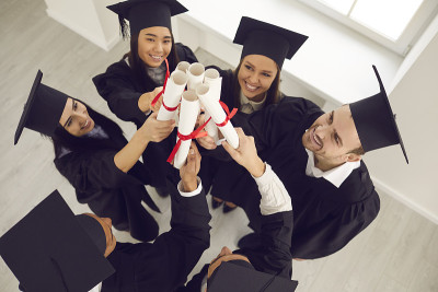 快乐的大学毕业生戴着传统的学术帽庆祝毕业