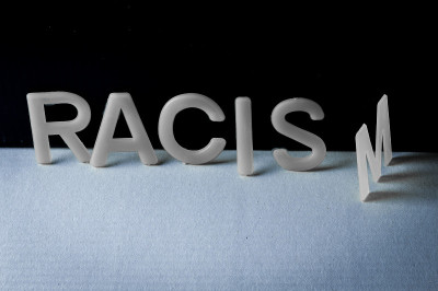 Drop racism(种族歧视)，单词写在双色调的背景上，最后一个字母翻了。反对种族主义的概念。
