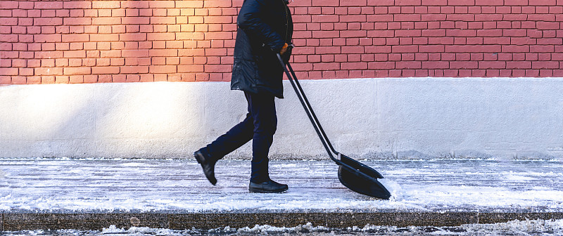 成年男子在铲城市街道上的雪