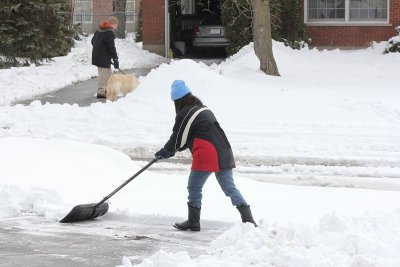 女士和邻居正在铲雪