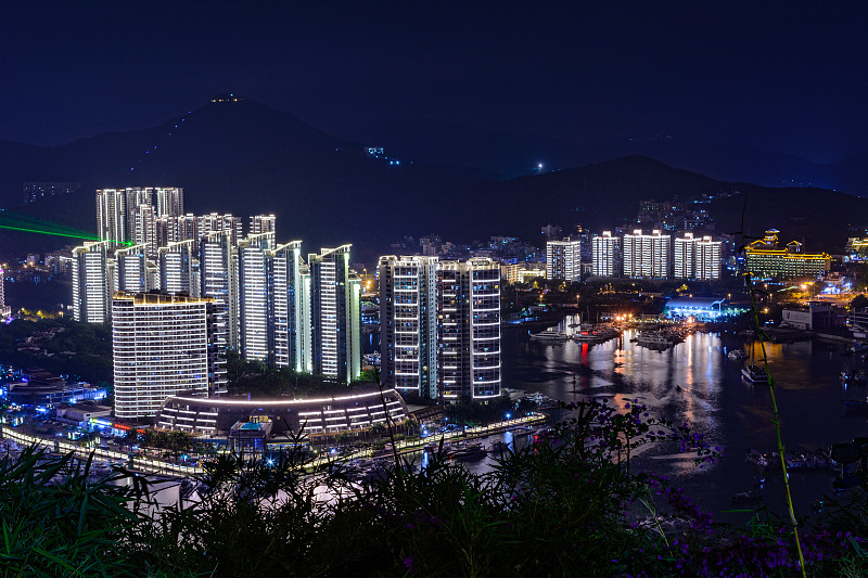 夜景三亚市与明亮的彩色照明建筑，结构，道路，人行道，杆子，桥梁。