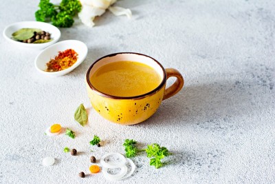 在一个碗(杯)里放上自制的鸡骨汤，配上蔬菜、香料和香草。动物来源的天然胶原蛋白。肉汤，鱼汤，蔬菜汤。