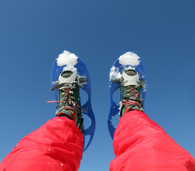 穿雪鞋在雪地上远足的登山者的腿