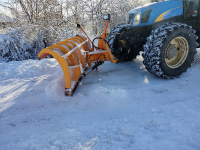 一辆轮式拖拉机将积雪推离路面
