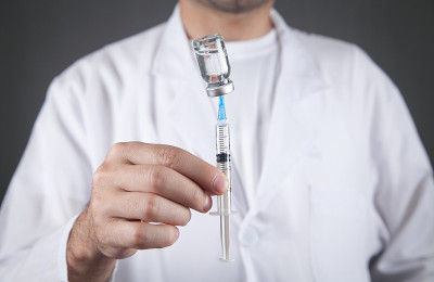 医生手持注射器和疫苗。