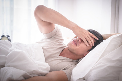 失眠的宿醉男子在床上头痛醒过来