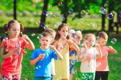 Group of children blowing soap bubbles in a garden