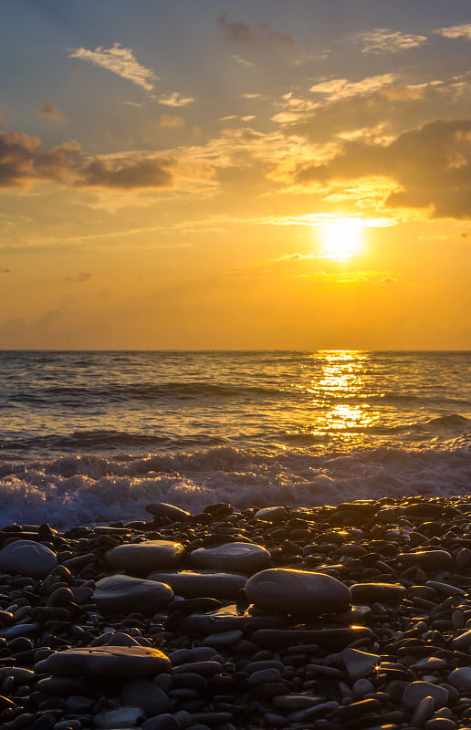 卵石滩上惊人的海上日落，太阳，海浪，云彩