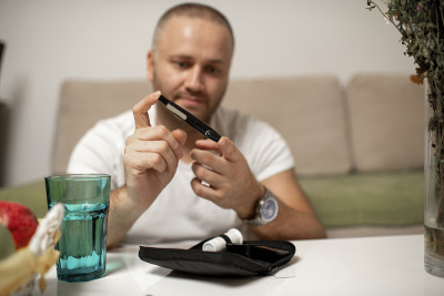 一个年轻人坐在家里的沙发上检查他的血糖水平